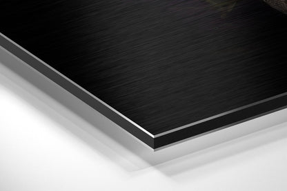 Close-up angled view of layered Black Swan Dibond panel showing brushed black aluminum surface with white foam core edge visible.