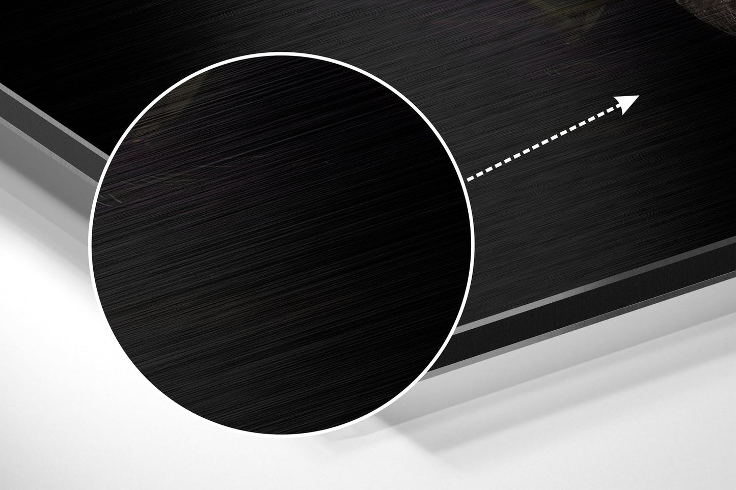 Close-up angled view of brushed black aluminium circular disc with white outline and directional arrow on dark textured background.