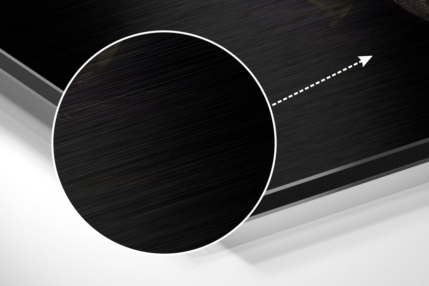 Close-up angled view of brushed black aluminium circular disc with white outline and directional arrow on dark textured background.