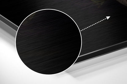 Close-up angled view of brushed black aluminium circular disc with white outline and directional arrow on dark textured background.