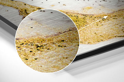 Close-up detail of golden marble brushed aluminum surface with black speckles and wood grain texture, magnified circular view.