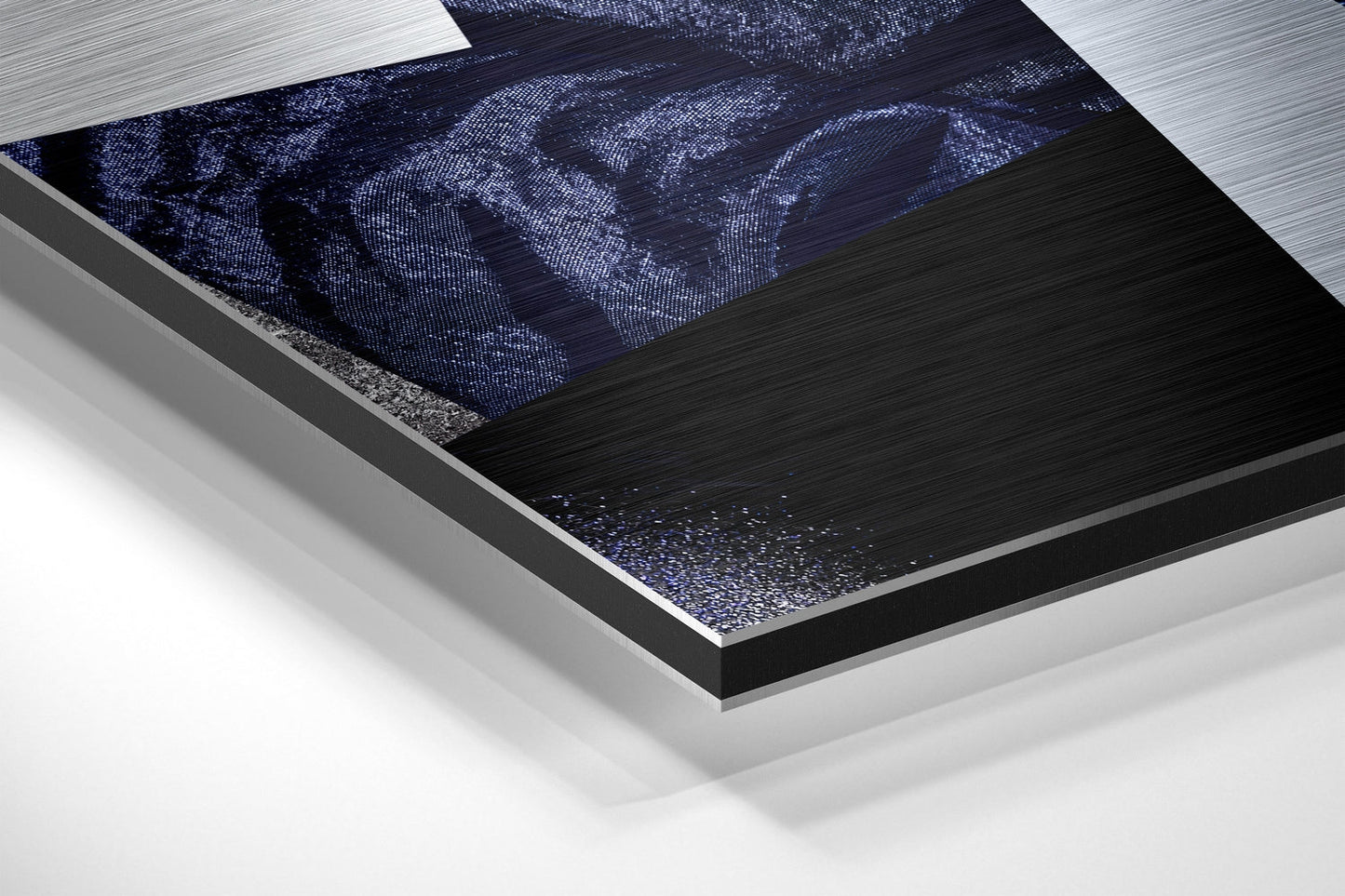 Angled close-up view of layered Dibond wall art showing brushed aluminum frame with dark textured surface and blue pixelated portrait detail.