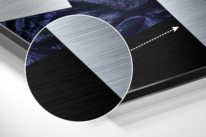 Close-up detail of brushed aluminium wall art showing metallic surface texture with black and white color blocking and circular magnified section.