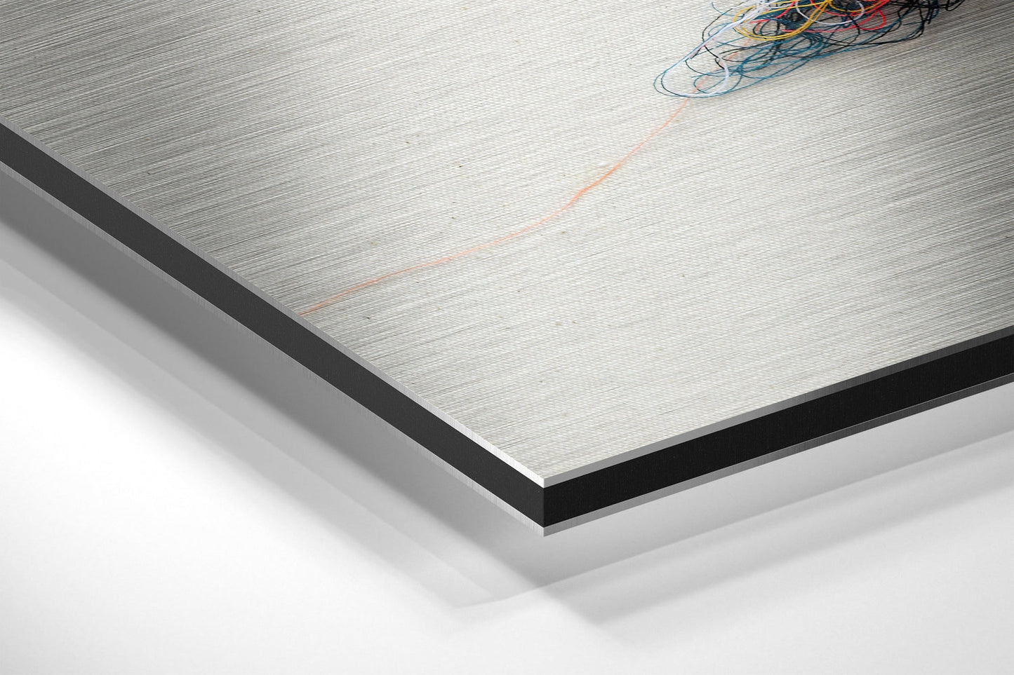 Close-up angled view of Sparrow Brushed Aluminium Dibond panel showing metallic surface texture with black edge trim and bundled wires.