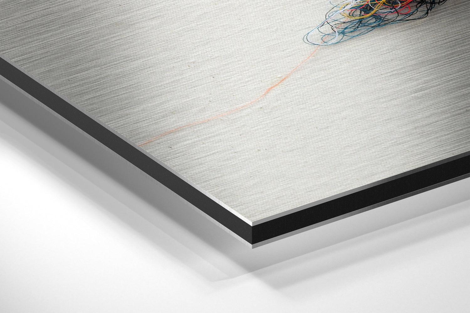 Close-up angled view of Sparrow Brushed Aluminium Dibond panel showing metallic surface texture with black edge trim and bundled wires.
