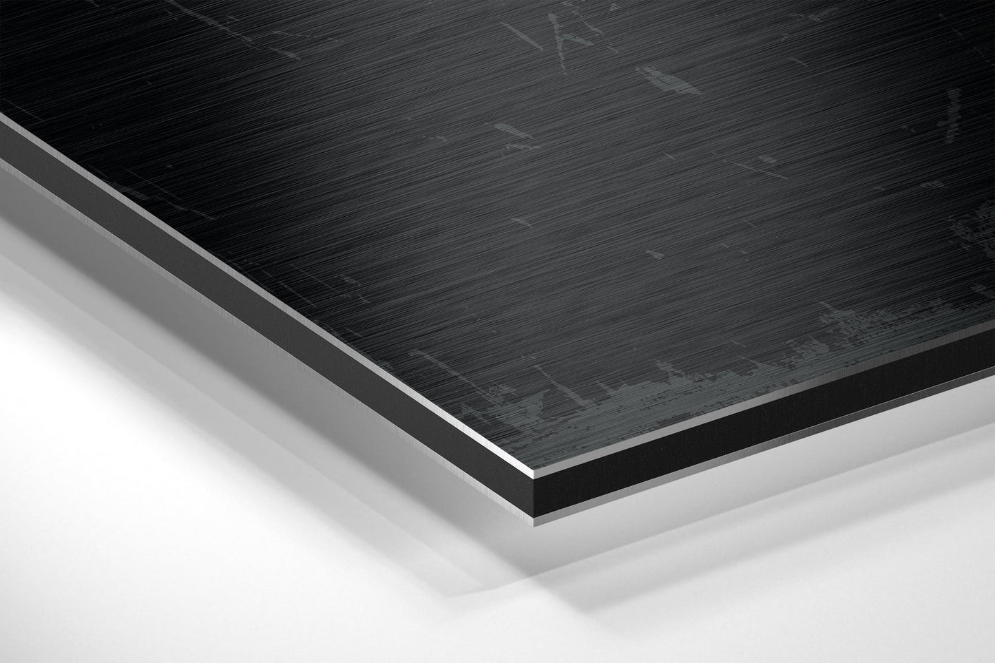 Close-up angled view of black brushed aluminum Dibond panel with white base layer visible beneath, showing layered construction and surface texture.