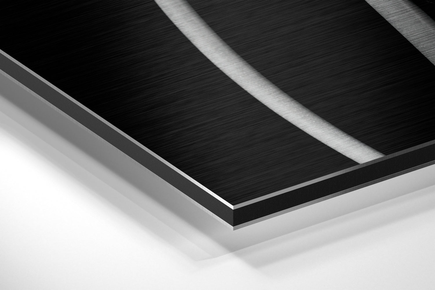 Close-up angled view of layered brushed aluminum and black Dibond panel edges showing metallic surface texture and depth.