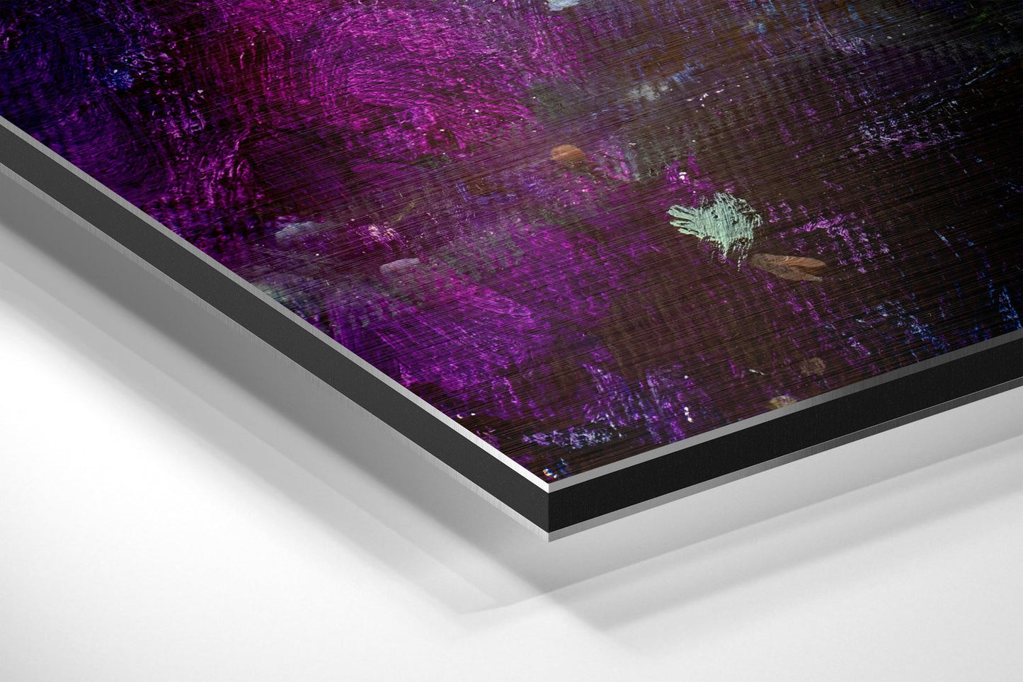 Angled corner view of framed brushed aluminium wall art featuring purple and dark abstract textured surface with white border detail.