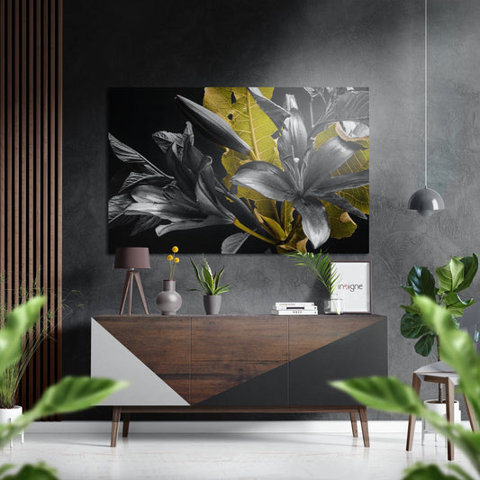Modern interior showroom featuring monochrome lilies with golden leaf accents mounted above wooden dresser with accessories.