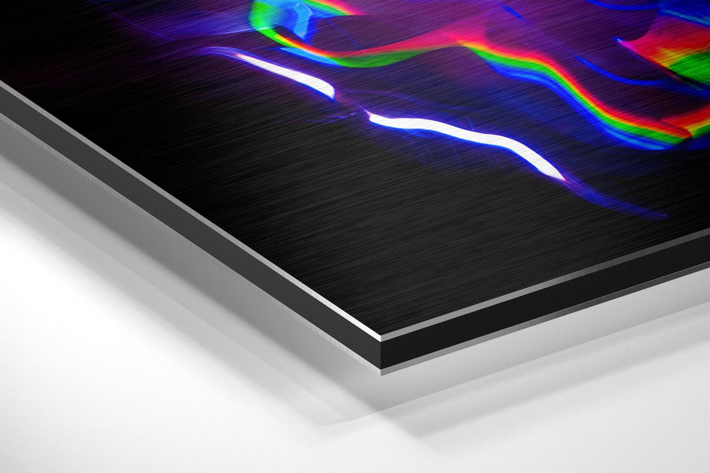 Angled perspective view of brushed aluminum Dibond panel showing layered edge construction with neon light streaks in white, blue, rainbow, and pink colors against black surface.