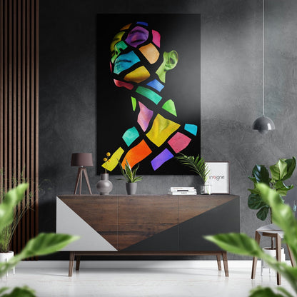 Colorful geometric pop art portrait with vibrant neon sections mounted on dark wall above wooden dresser in modern interior setting.