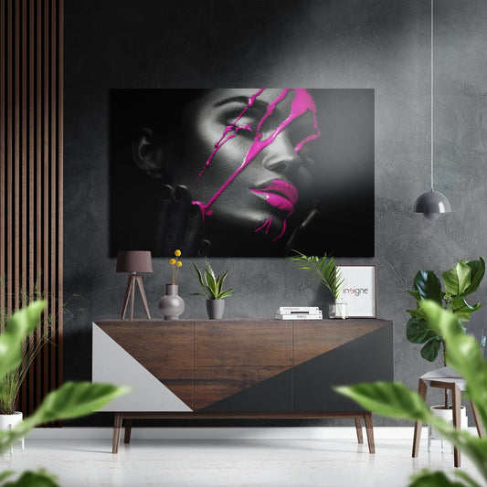 Modern living room with abstract black and white portrait featuring bright pink geometric line art displayed above a wooden console table with plants and decor.