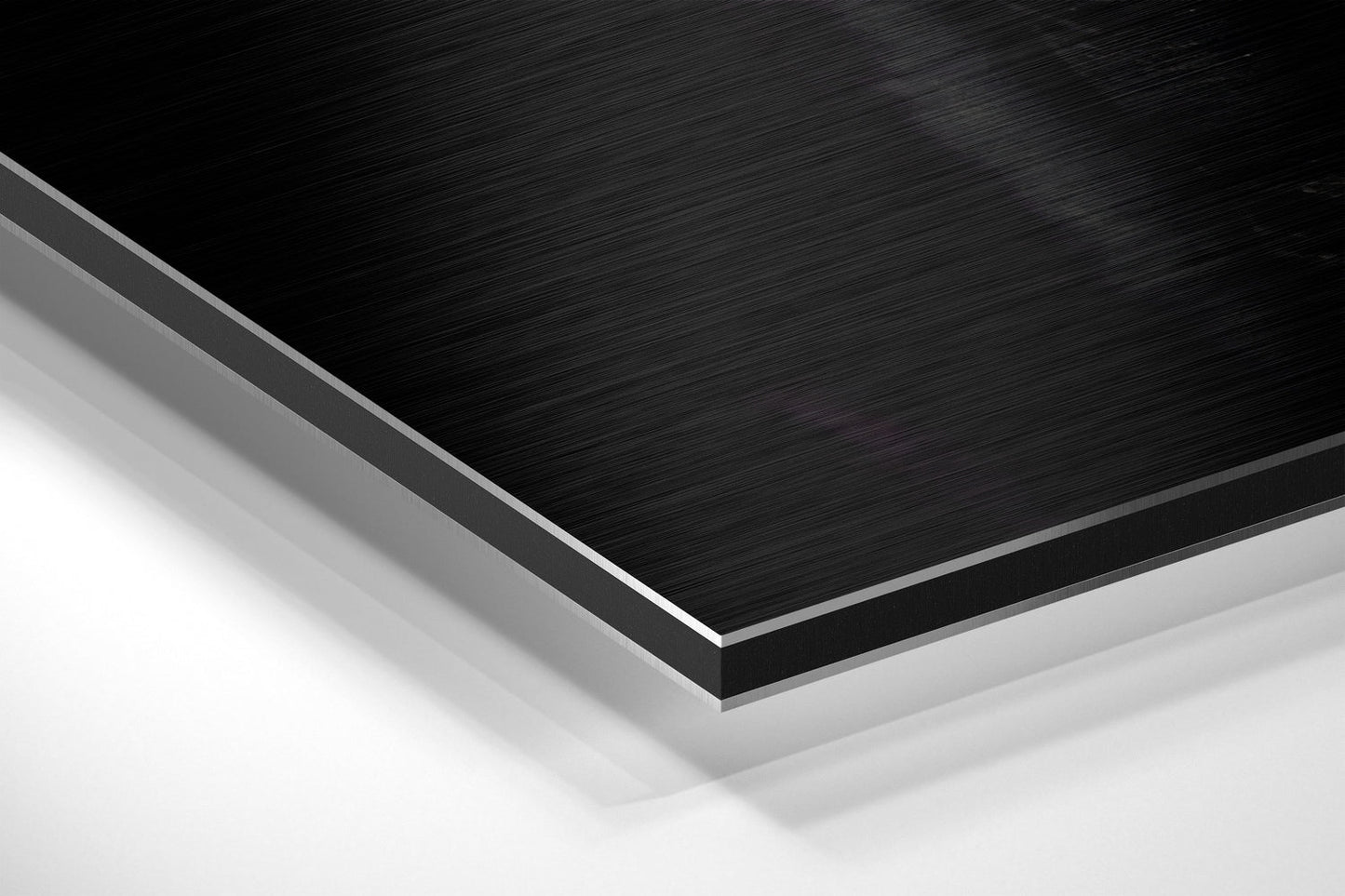 Close-up angled view of layered brushed black and white aluminum composite material showing edge detail and surface texture.