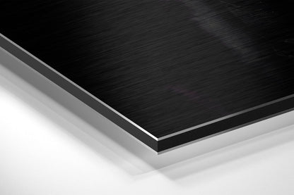 Close-up angled view of layered brushed black and white aluminum composite material showing edge detail and surface texture.