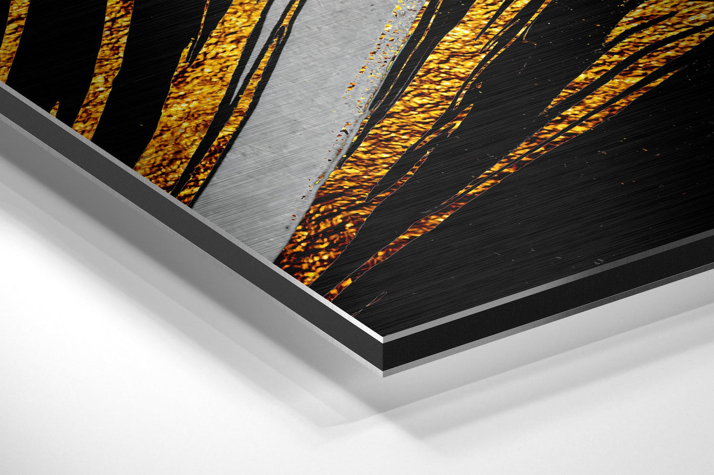 Close-up angled view of layered Dibond print showing gold and black feather design with brushed aluminum surface and white mounting edge.