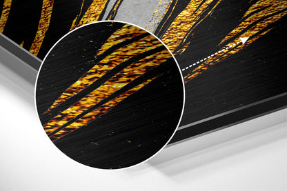 Close-up detail of golden and yellow brushed aluminum surface with diagonal striped texture pattern and black background.