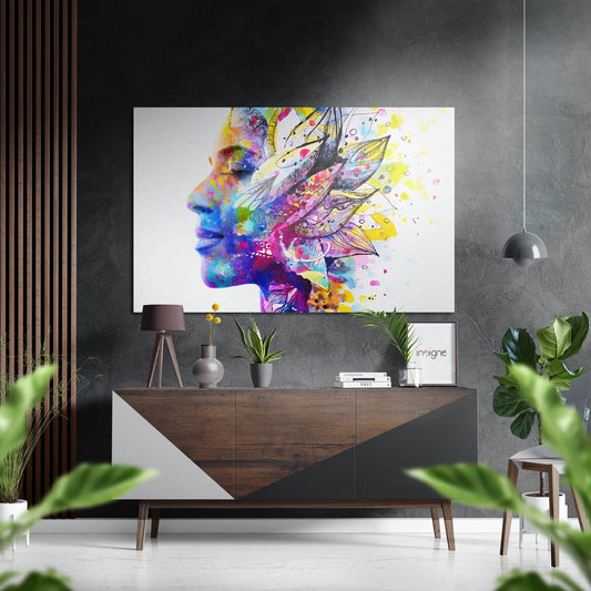 Colorful abstract profile of a head with multicolored watercolor splashes and decorative line art displayed above a wooden console table in a modern interior setting.