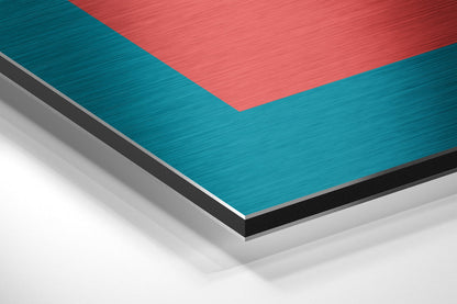 Layered stack of brushed aluminium Dibond sheets displaying teal, coral red, black, and white panels with metallic brushed finishes.