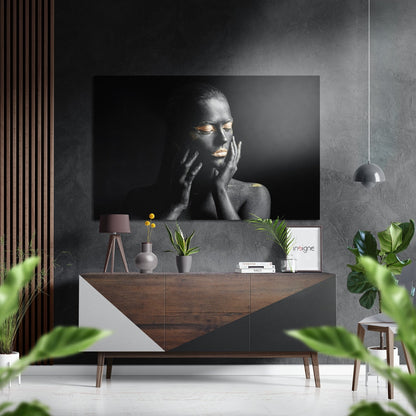 Black and white portrait of a woman with gold accents displayed on brushed aluminium above a wooden sideboard in a modern interior setting.