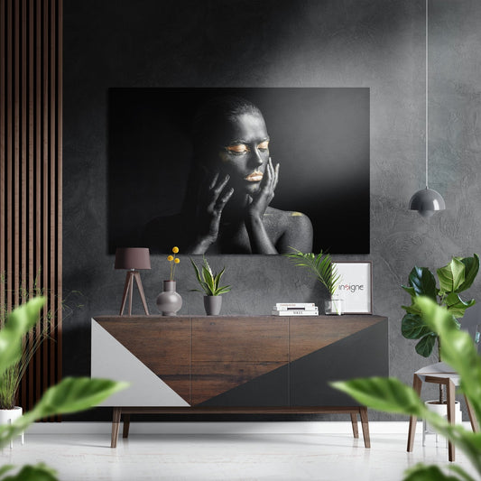 Black and white portrait of a woman with gold accents displayed on brushed aluminium above a wooden sideboard in a modern interior setting.