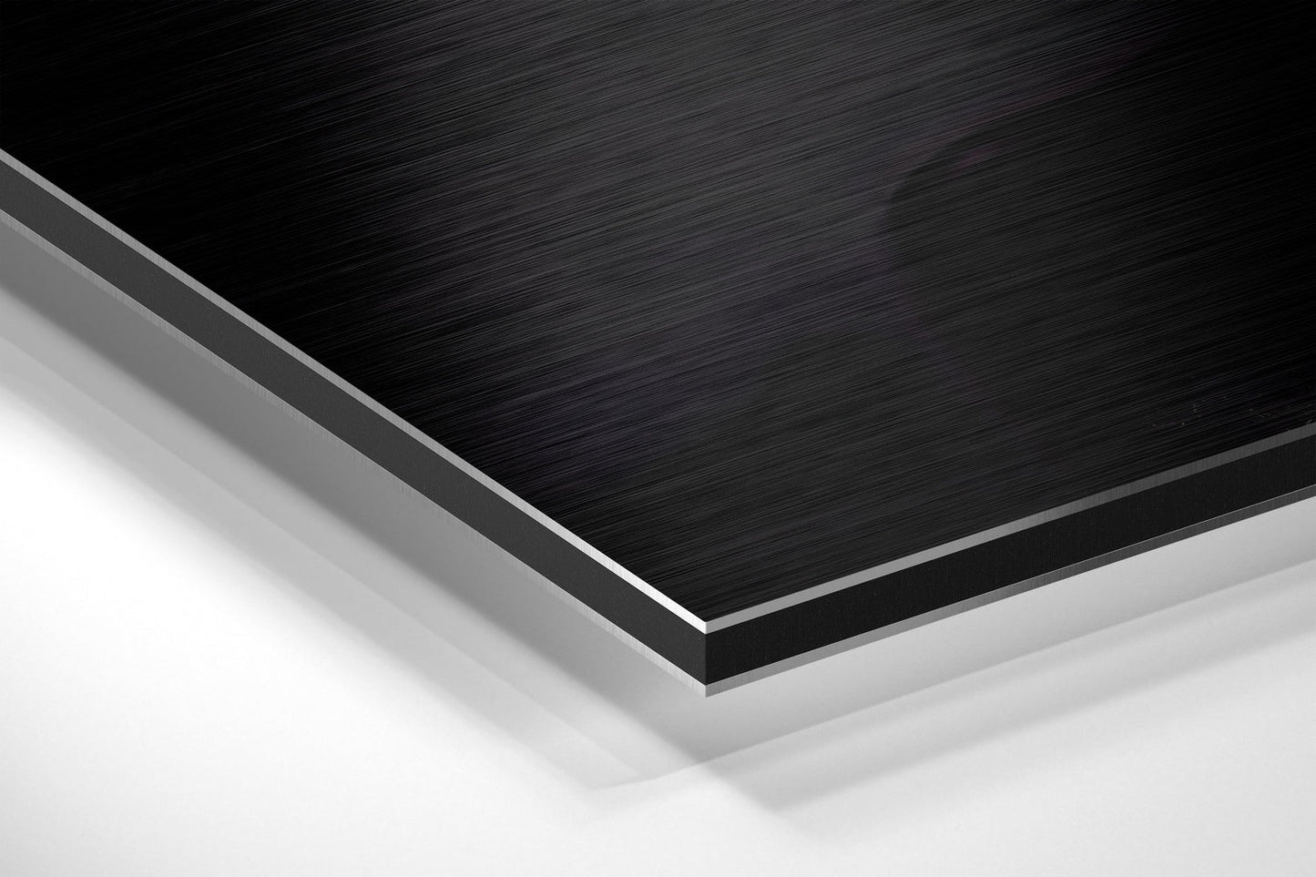 Close-up angled view of layered Dibond panel showing black brushed aluminum surface with gray and white backing layers.