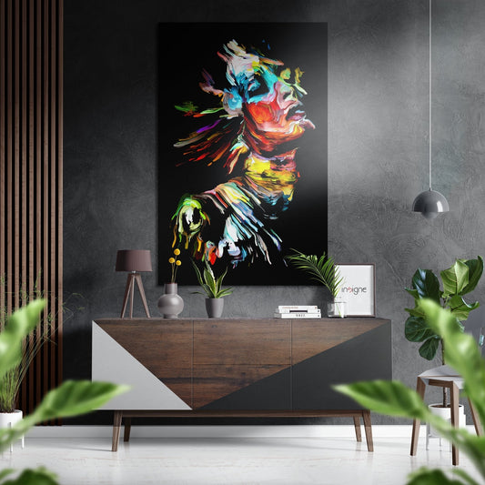 Colorful neon brushstroke portrait of a woman's profile mounted above a wooden console table in a modern interior with plants and pendant lighting.