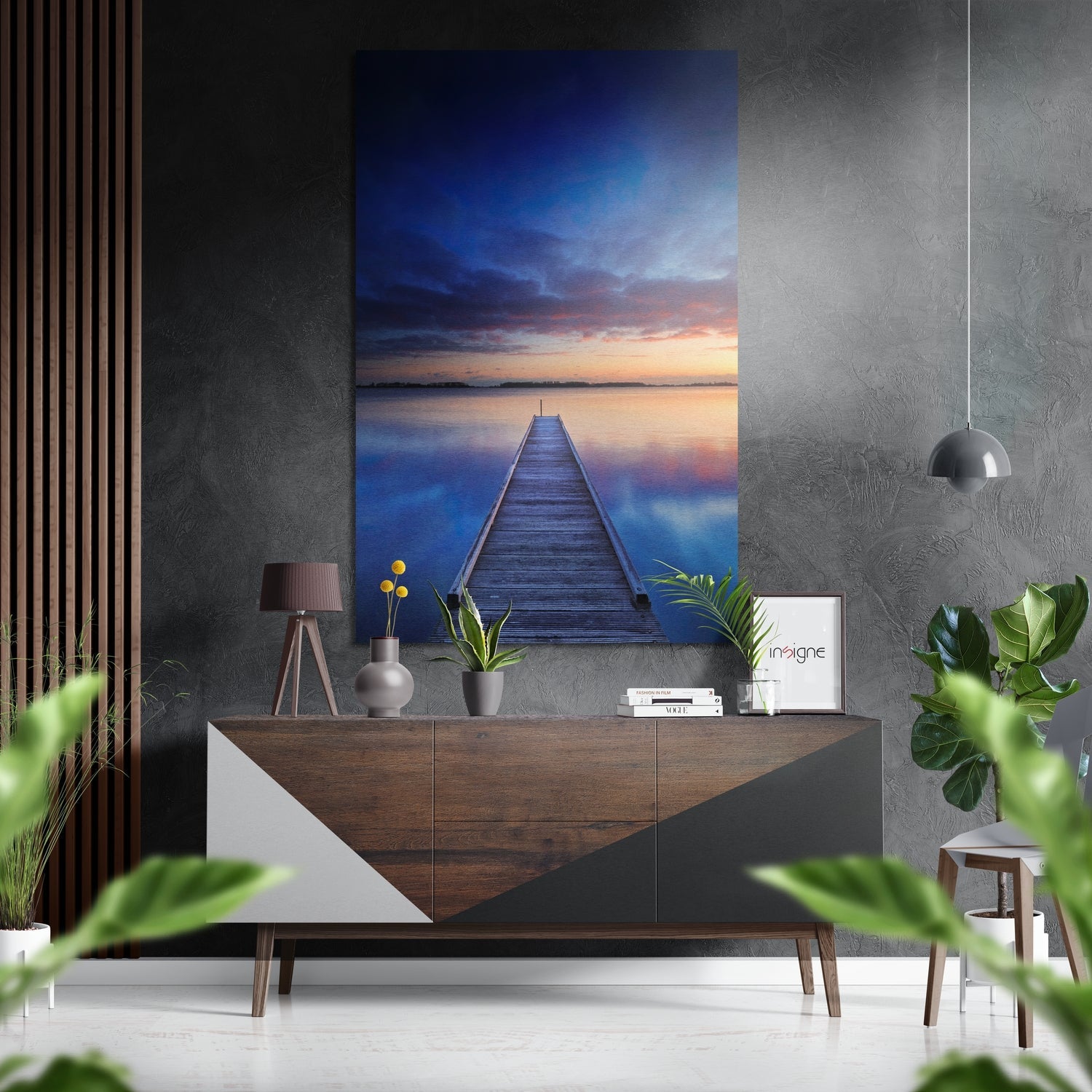 Brushed aluminium Dibond wall art depicting a wooden boardwalk extending into calm water at sunset, displayed above a mid-century modern console table in a contemporary interior setting.