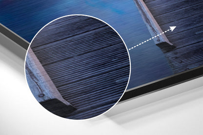 Close-up detail of brushed aluminum Dibond wall art showing horizontal linear texture and blue water reflection surface with white border circle.