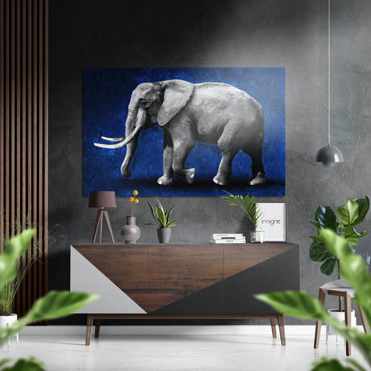 Gray elephant with ivory tusks on deep blue background, displayed above wooden console table in modern interior setting.