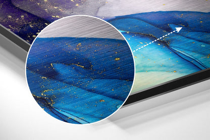 Close-up detail of brushed blue and purple aluminum surface with gold leaf accents and magnified circular view showing texture.