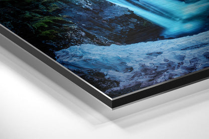 Angled view of brushed aluminium Dibond wall art displaying a glacier landscape with blue ice, dark rock, and flowing water detail.