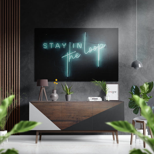 Modern living room with neon "Stay in the Loop" sign displayed above wooden credenza with potted plants and pendant lighting.