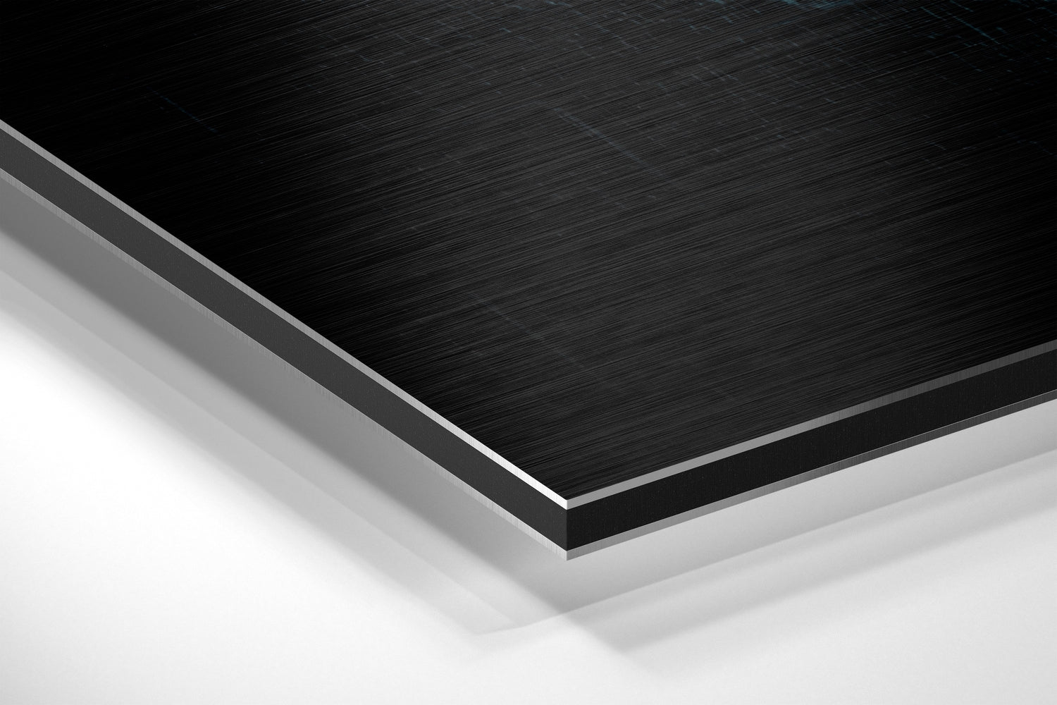 Close-up angled view of layered Dibond panel showing brushed black aluminum surface with gray and white backing layers.