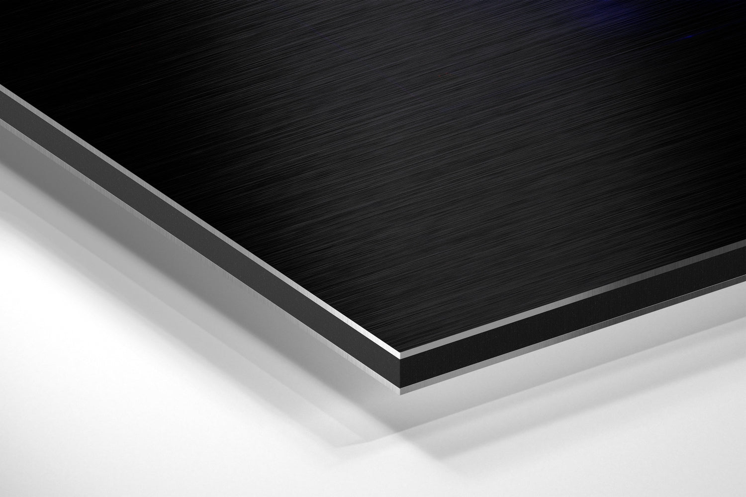 Close-up angled view of layered Dibond panel showing black brushed aluminum top surface with gray and white composite layers beneath.