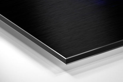 Close-up angled view of layered Dibond panel showing black brushed aluminum top surface with gray and white composite layers beneath.