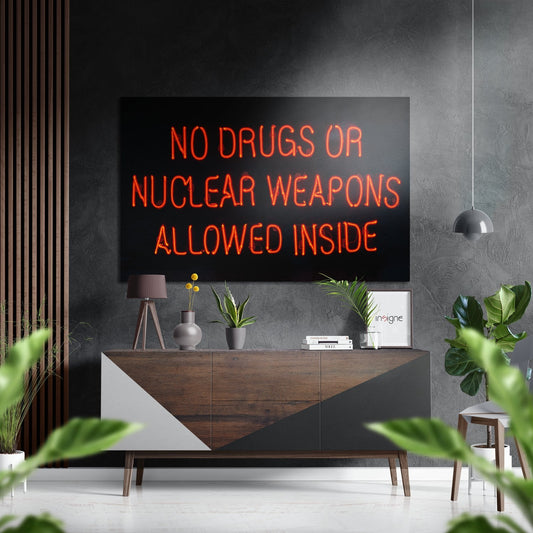 Red neon sign reading "NO DRUGS OR NUCLEAR WEAPONS ALLOWED INSIDE" mounted on dark wall above wooden console table in modern interior.