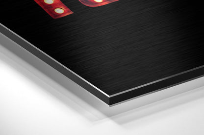 Angled perspective view of brushed aluminum Dibond wall art showing layered black and silver edges with red illuminated elements visible at top.
