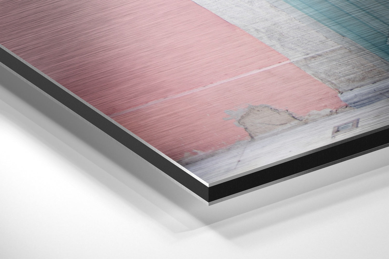Close-up angled view of layered aluminum dibond construction showing pink, white, and teal brushed metal panels with black backing layer.