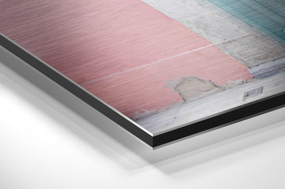 Close-up angled view of layered aluminum dibond construction showing pink, white, and teal brushed metal panels with black backing layer.