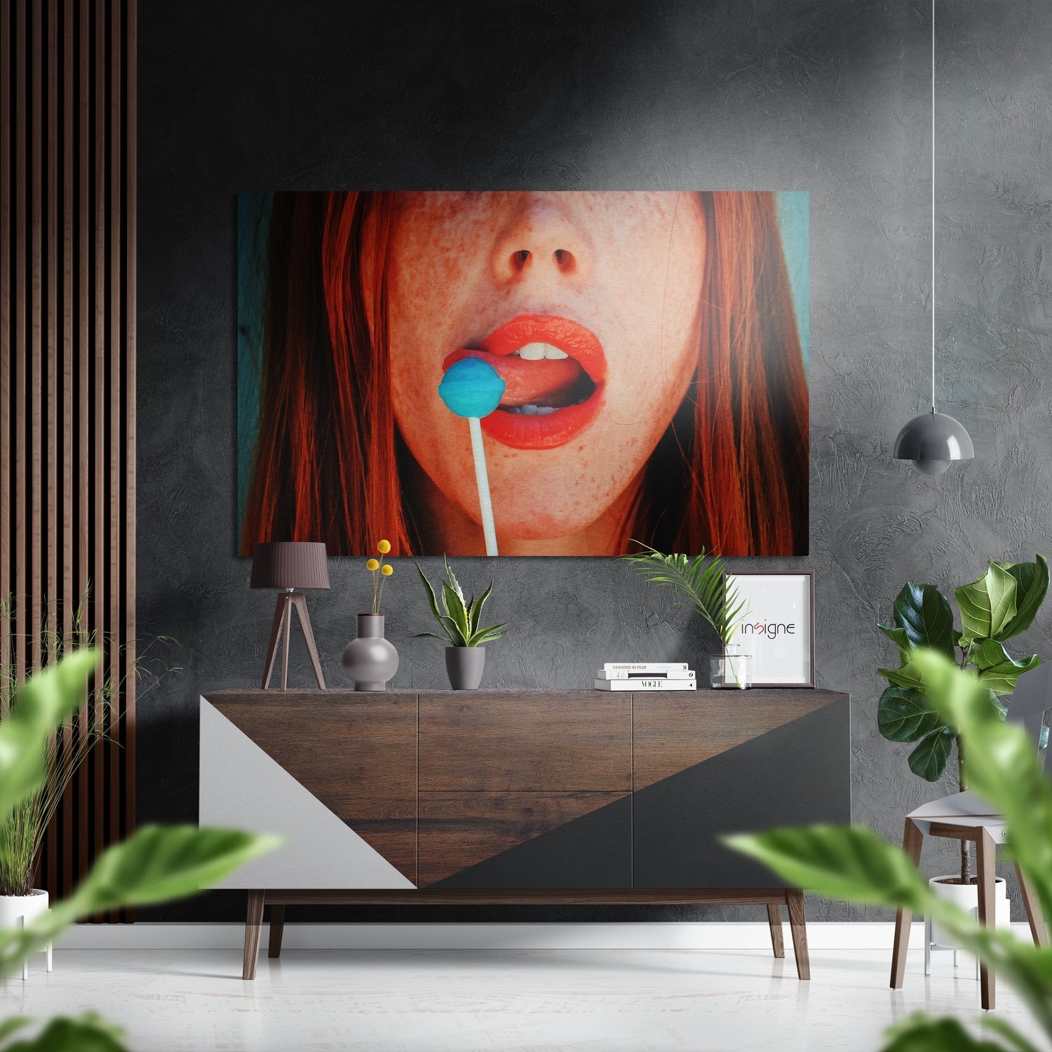 Modern interior showing red-haired figure with blue lollipop on brushed aluminum wall art above wooden console table.