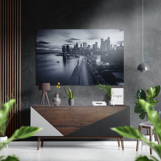 Monochrome Manhattan skyline photograph mounted on grey textured wall above wooden console table with plants and accessories.