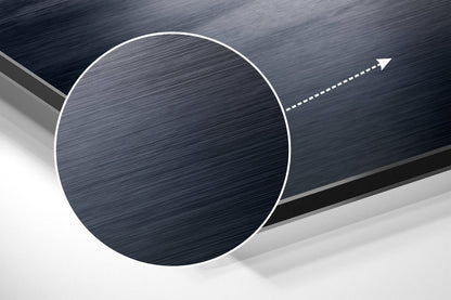 Angled close-up of brushed aluminum circular wall art with white border and directional arrow against layered gray background.