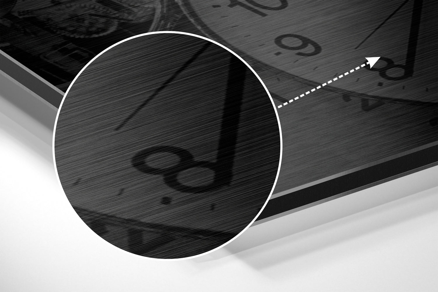 Close-up detail of brushed aluminium surface with circular magnified section revealing embossed infinity symbol and directional arrow graphic.