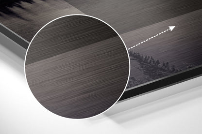 Angled perspective view of circular brushed aluminum wall art with white border and directional arrow, mounted on textured gray surface.