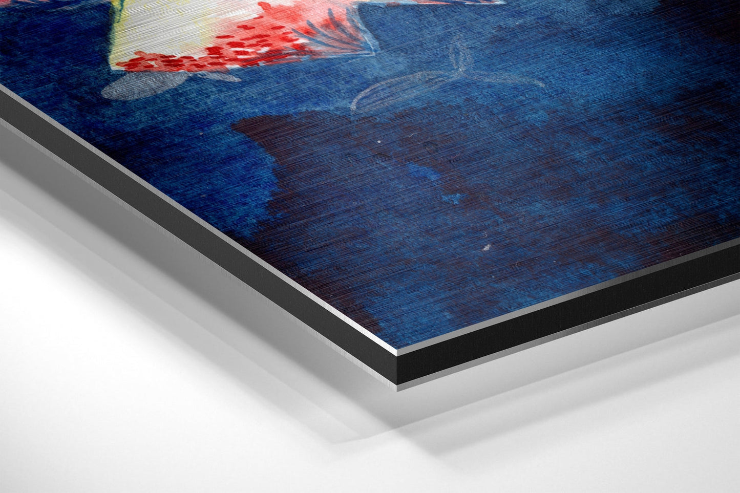 Close-up angled view of brushed aluminium Dibond wall art showing layered edges and fish artwork with red and blue tones on dark background.