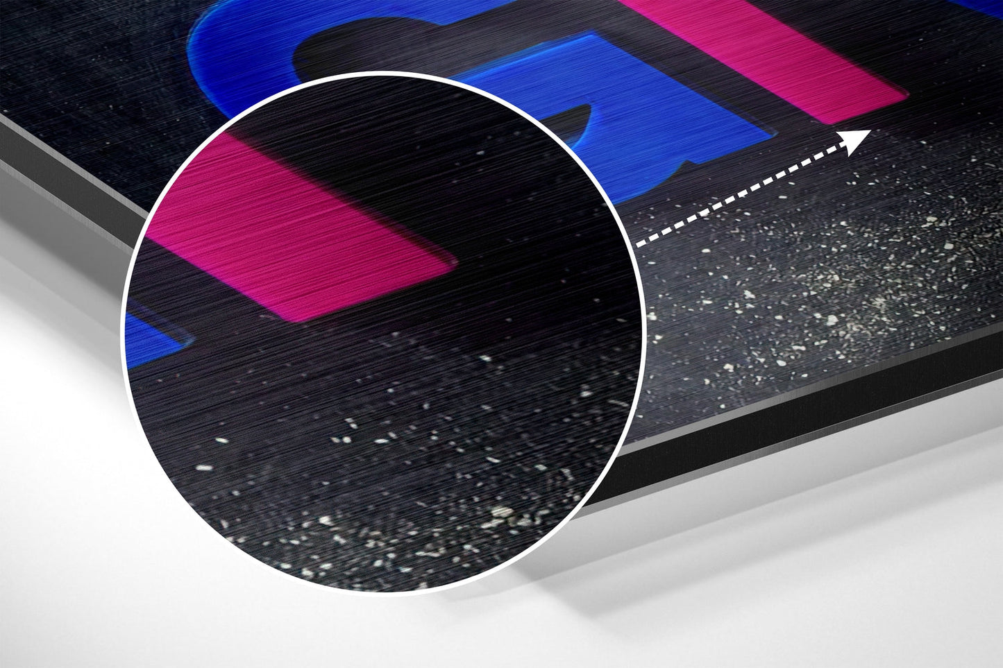 Close-up detail of brushed aluminum surface showing black texture with blue and magenta geometric shapes and white speckled finish.