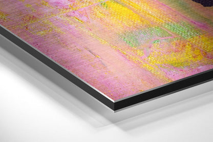 Close-up angled view of layered aluminum dibond showing pink, yellow, and green brushed metal surface with textured finish and black edge detail.