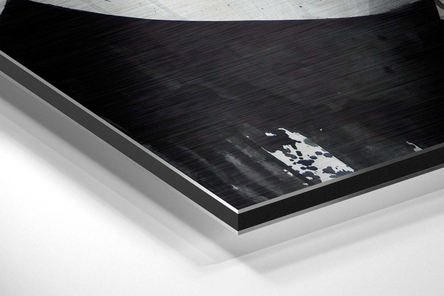 Angled perspective view of brushed aluminum Dibond wall art with white and blue abstract design on black surface.