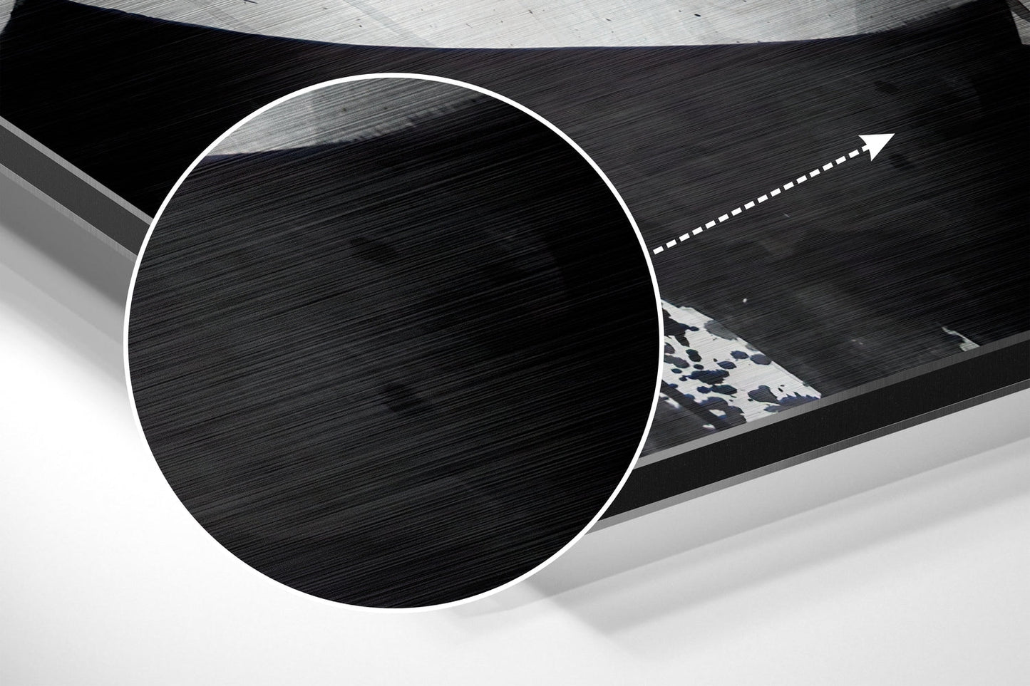 Close-up angled view of circular brushed aluminum wall art with white border and blue patterned triangular detail visible through opening.