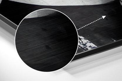 Close-up angled view of circular brushed aluminum wall art with white border and blue patterned triangular detail visible through opening.